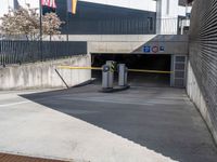 a parking garage in a building with the door open to the inside, at the end, there are barriers and several signs on it