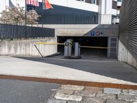 a parking garage in a building with the door open to the inside, at the end, there are barriers and several signs on it