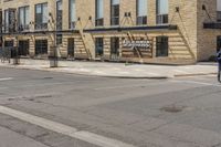 an empty sidewalk with a building and a street sign on it and a traffic light in front