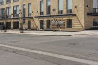 an empty sidewalk with a building and a street sign on it and a traffic light in front