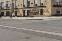 an empty sidewalk with a building and a street sign on it and a traffic light in front