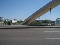 a truck driving across a bridge near a street corner near buildings and a bridge with many cables