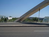 a truck driving across a bridge near a street corner near buildings and a bridge with many cables