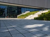 a large building with stairs and bushes near by it's doors and stairs outside