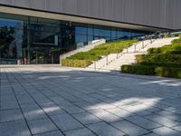 a large building with stairs and bushes near by it's doors and stairs outside