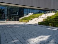 a large building with stairs and bushes near by it's doors and stairs outside