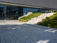 a large building with stairs and bushes near by it's doors and stairs outside