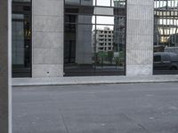 the black car is parked at the curb of a large building in the city center