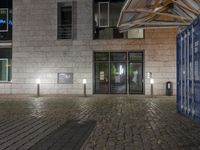 there is an empty building with glass windows and lights on at the entrance of it