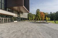 a paved stone courtyard has a large stone block on the right side and a tall modern building to the left