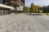 a paved stone courtyard has a large stone block on the right side and a tall modern building to the left