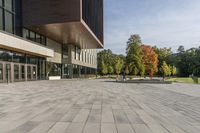 a paved stone courtyard has a large stone block on the right side and a tall modern building to the left