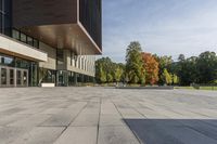 a paved stone courtyard has a large stone block on the right side and a tall modern building to the left