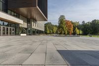 a paved stone courtyard has a large stone block on the right side and a tall modern building to the left