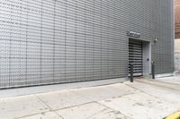 a building with grey paint next to a sidewalk and hydrant on the ground below it