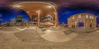 fisheye view of a building in a city center at night with buildings in the background