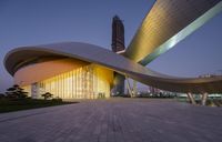 a modern building has many curved windows and a yellow facade that overlooks the city's lights