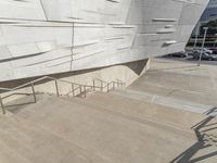 a picture of a staircase leading up to a building on a city street in front of parking lot