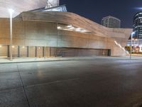 the building is lit up at night time with city street lights in the foreground