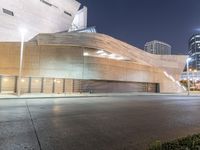 the building is lit up at night time with city street lights in the foreground