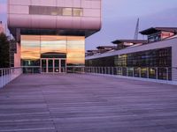 a building has glass windows and is lit up at dusk on the deck with its lights on