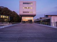 a building has glass windows and is lit up at dusk on the deck with its lights on