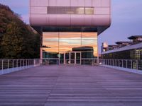 a building has glass windows and is lit up at dusk on the deck with its lights on