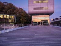 a building has glass windows and is lit up at dusk on the deck with its lights on