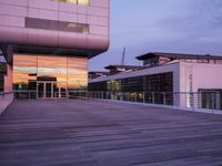 a building has glass windows and is lit up at dusk on the deck with its lights on