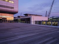 a building has glass windows and is lit up at dusk on the deck with its lights on