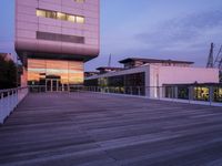 a building has glass windows and is lit up at dusk on the deck with its lights on