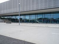 an exterior view of the outside of a building with glass and metal clad walls on either side, on a flat surface