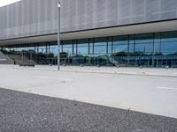 an exterior view of the outside of a building with glass and metal clad walls on either side, on a flat surface