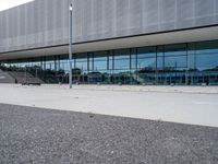 an exterior view of the outside of a building with glass and metal clad walls on either side, on a flat surface