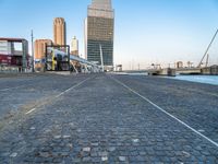 a building near the ocean with a bridge above it on a cobble stone walkway