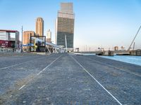 a building near the ocean with a bridge above it on a cobble stone walkway