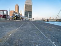 a building near the ocean with a bridge above it on a cobble stone walkway