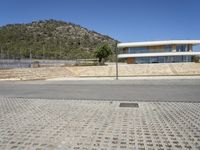 a large building with an open courtyard and paved walkways leading to it in front of a mountain