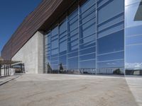 an outdoor building has a long balcony and glass walls that overlook the mountains outside from each window