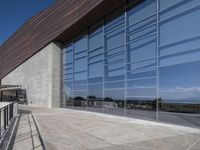 an outdoor building has a long balcony and glass walls that overlook the mountains outside from each window