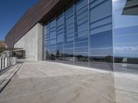 an outdoor building has a long balcony and glass walls that overlook the mountains outside from each window