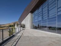 an outdoor building has a long balcony and glass walls that overlook the mountains outside from each window