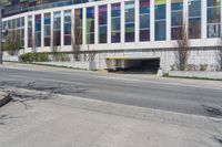 an empty street by a building on the other side of the road, and an entrance to it,