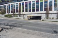 an empty street by a building on the other side of the road, and an entrance to it,