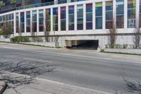 an empty street by a building on the other side of the road, and an entrance to it,