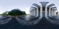 a fish eye photo of a building with arches above a pool in a park near the river