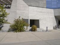 a white brick building with stairs leading to a large windowed opening and grass growing on the side