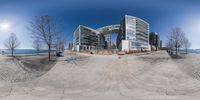 there is a fish eye lens shot of a building by the water and some benches