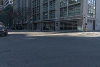 the view of a cross walk across the road from a building and in between two parked cars