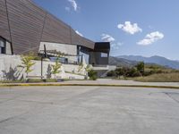 the concrete walkway has a railing that extends the building's roof onto the mountains